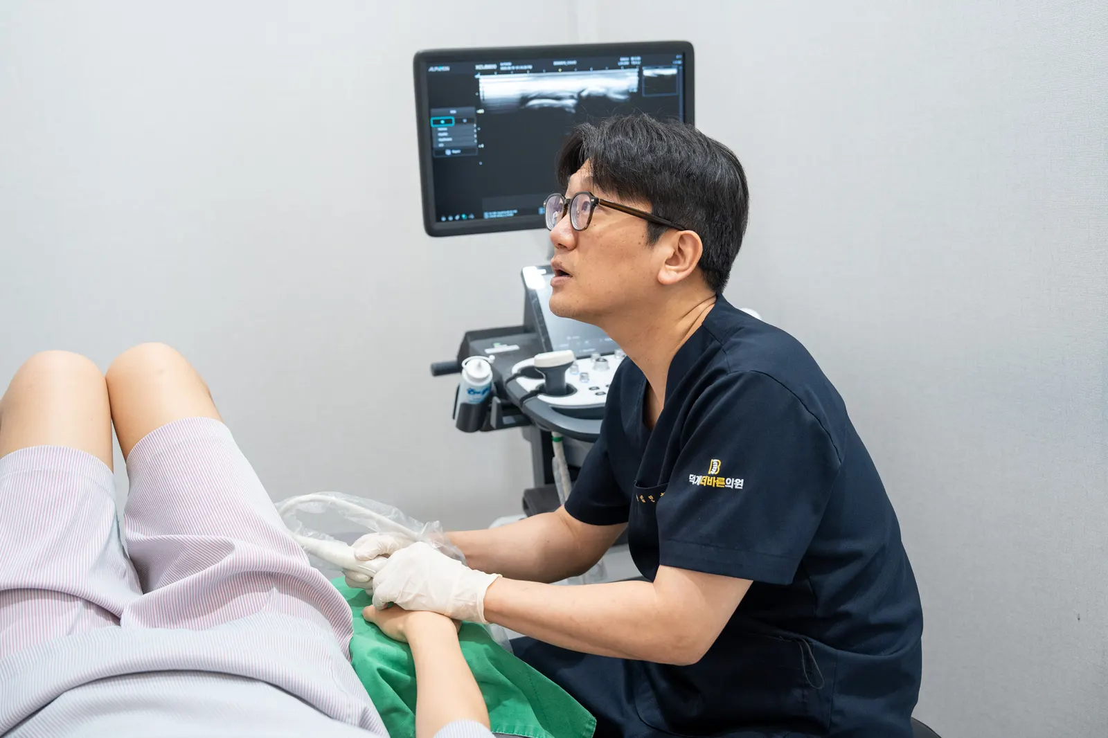 진찰대에서 초음파로 무릎 부위를 확인하는 모습